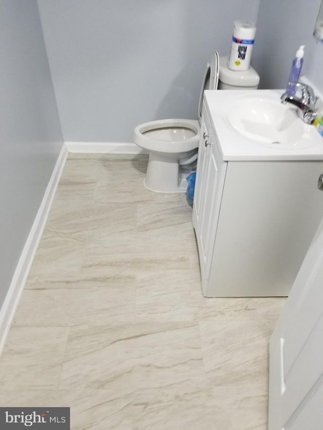 bathroom with toilet, vanity, and baseboards