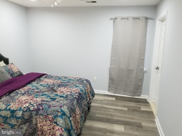 bedroom with visible vents, wood finished floors, and baseboards