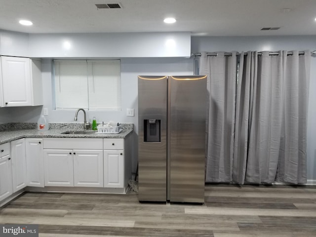 kitchen featuring a sink, light wood finished floors, stainless steel refrigerator with ice dispenser, and white cabinetry