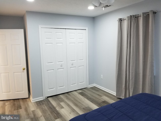 unfurnished bedroom featuring a closet, visible vents, baseboards, and wood finished floors