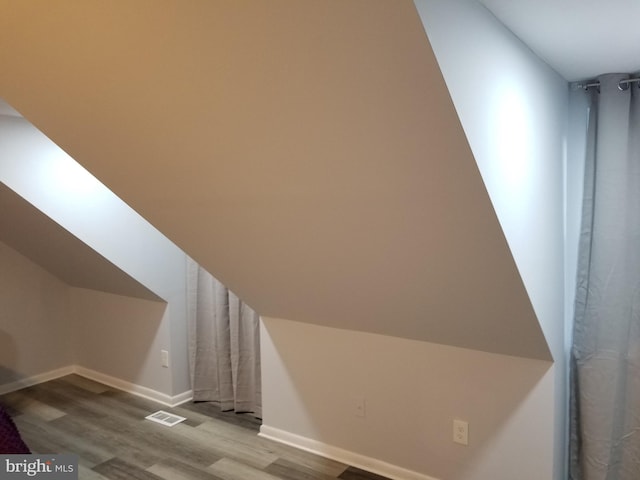 additional living space with vaulted ceiling, wood finished floors, and baseboards