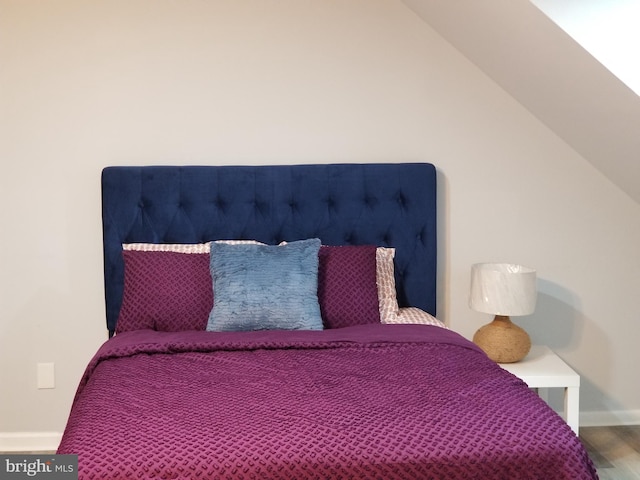 bedroom featuring baseboards, lofted ceiling, and wood finished floors