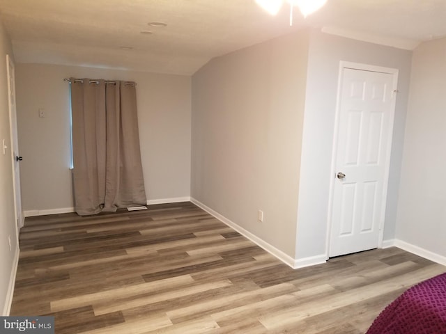 spare room with baseboards and wood finished floors