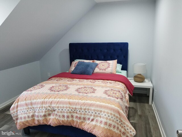 bedroom featuring baseboards, lofted ceiling, and wood finished floors