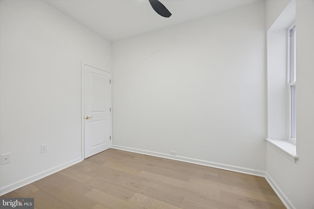 spare room featuring a wealth of natural light, baseboards, and wood finished floors