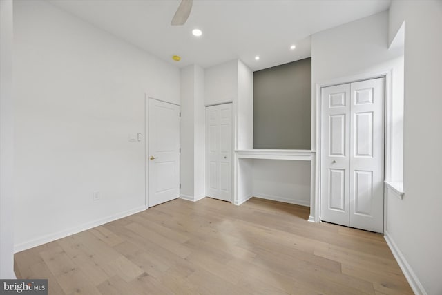 unfurnished bedroom with wood finished floors, baseboards, recessed lighting, ceiling fan, and two closets