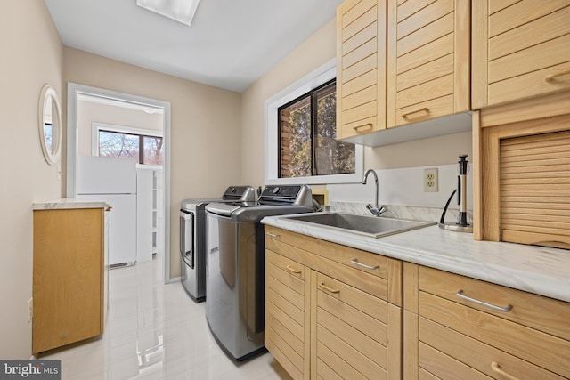 clothes washing area with a sink, cabinet space, and washer and clothes dryer