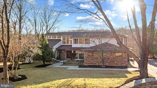 view of front of home with a front yard and stone siding