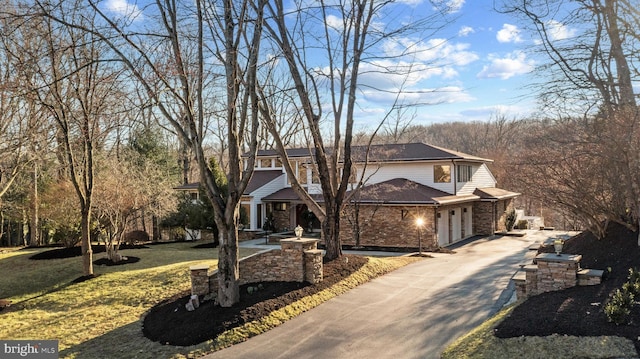 view of front facade featuring brick siding, a front lawn, concrete driveway, and a garage