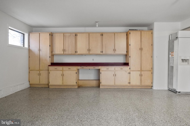 kitchen featuring dark countertops, built in desk, light speckled floor, and white fridge with ice dispenser