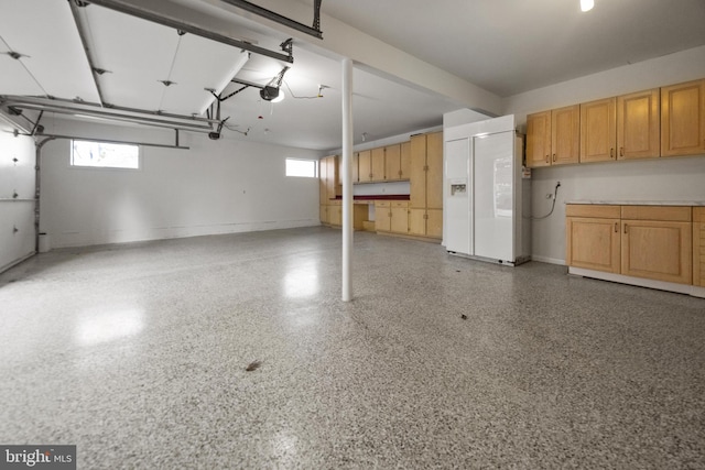 garage with baseboards, white fridge with ice dispenser, and a garage door opener