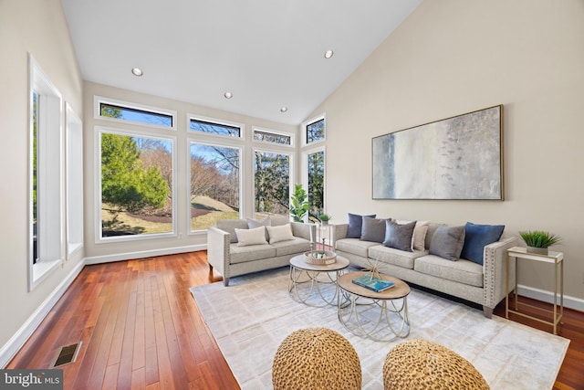 living room featuring visible vents, baseboards, recessed lighting, high vaulted ceiling, and wood-type flooring