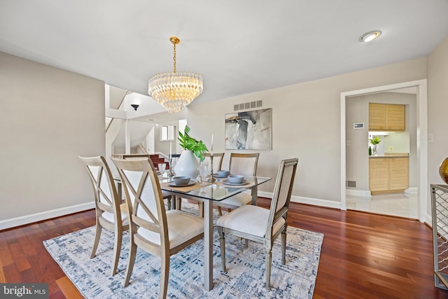 dining space with a notable chandelier, visible vents, baseboards, and hardwood / wood-style flooring