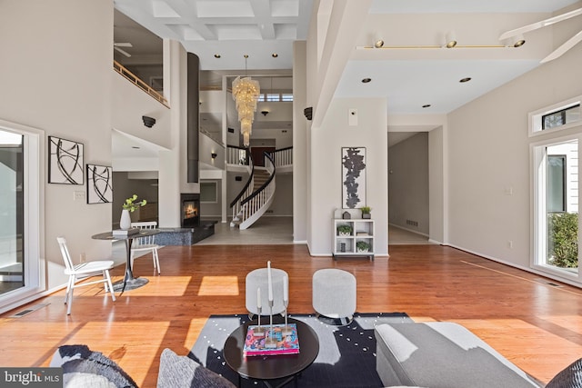 living area with stairway, wood finished floors, a glass covered fireplace, and a towering ceiling