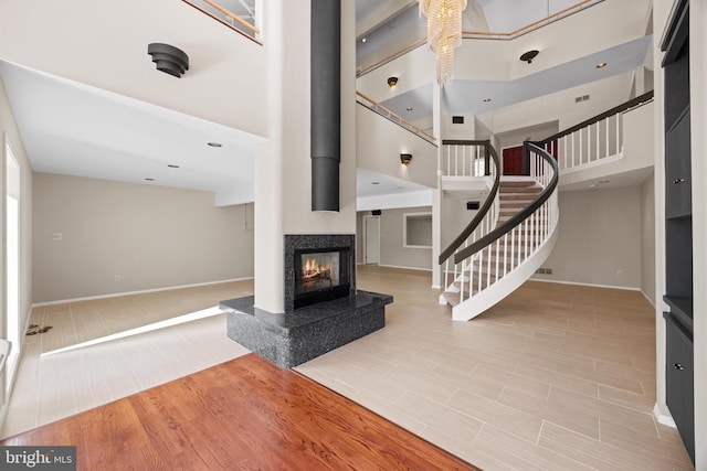 interior space with stairway, baseboards, a towering ceiling, and wood finish floors