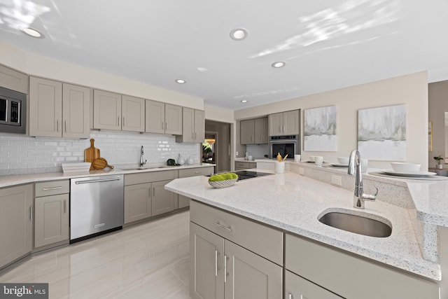 kitchen featuring backsplash, gray cabinetry, stainless steel appliances, and a sink