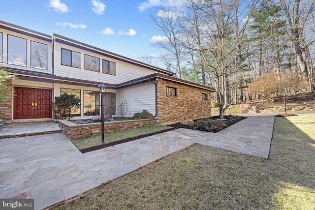 view of side of home featuring a lawn and stone siding