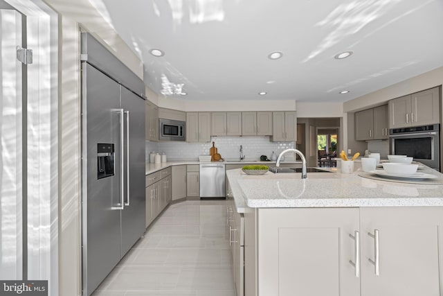 kitchen featuring a sink, gray cabinetry, tasteful backsplash, and stainless steel appliances