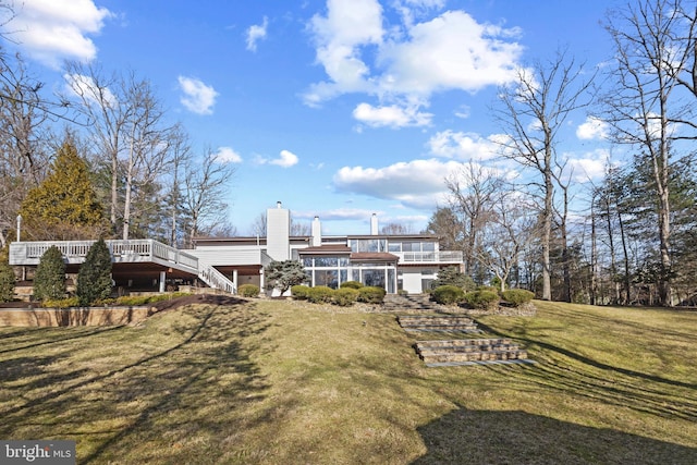 rear view of property with stairway, a chimney, a yard, and a deck