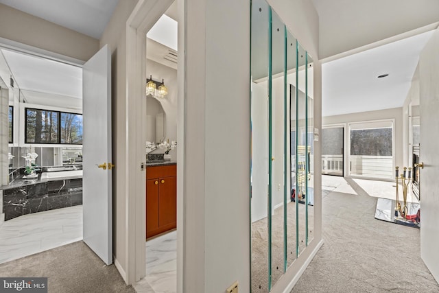 hall with a wealth of natural light, carpet flooring, and marble finish floor