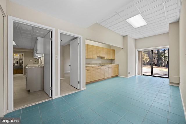 unfurnished living room featuring a sink, a paneled ceiling, baseboards, and dark tile patterned flooring