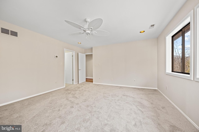 carpeted spare room featuring visible vents, a ceiling fan, and baseboards