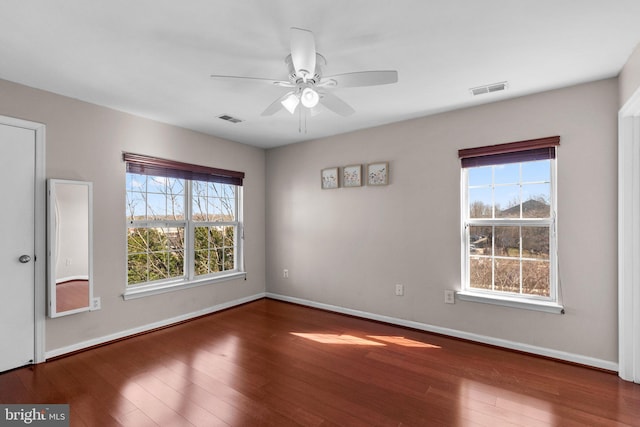 unfurnished room featuring visible vents, wood-type flooring, and baseboards