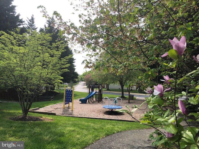 view of home's community featuring playground community and a yard