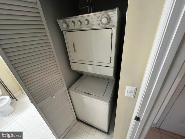 laundry area featuring stacked washer and dryer, light tile patterned flooring, and laundry area