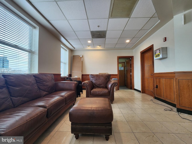 living room featuring visible vents, wainscoting, and a paneled ceiling