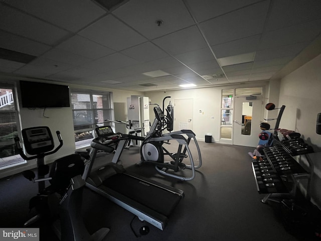 gym featuring baseboards and a drop ceiling