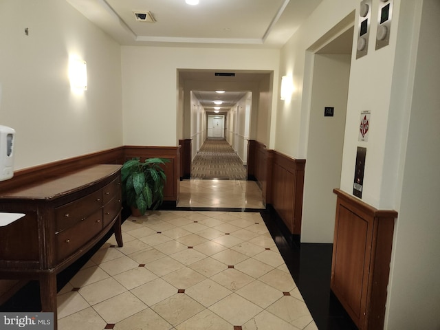 hall featuring visible vents, wainscoting, and a tray ceiling