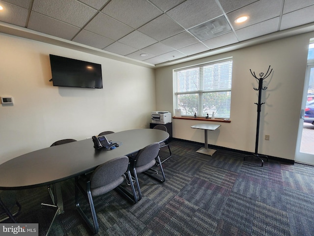 office area featuring a drop ceiling, baseboards, and dark carpet