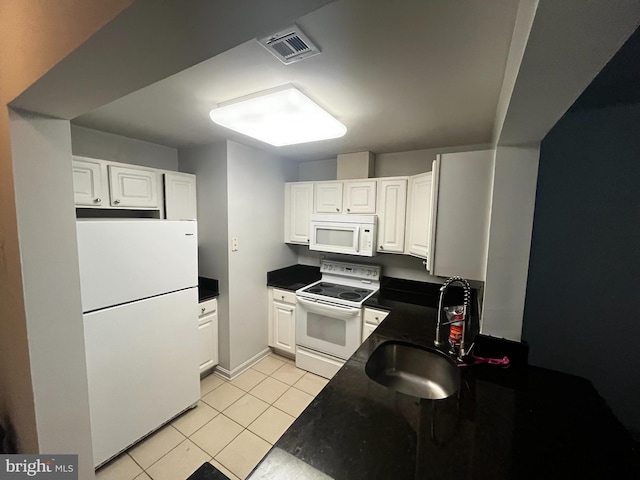 kitchen featuring visible vents, a sink, dark countertops, white appliances, and light tile patterned flooring