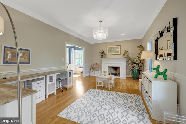 living area featuring light wood-style floors, ornamental molding, a fireplace with flush hearth, and a notable chandelier