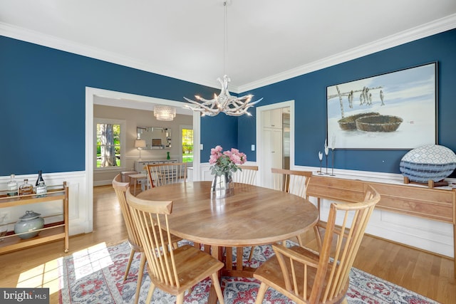 dining room with crown molding, wainscoting, wood finished floors, and a chandelier