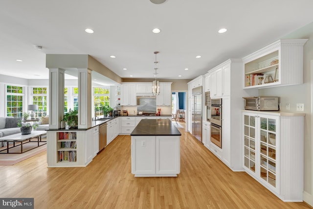 kitchen featuring dark countertops, appliances with stainless steel finishes, open shelves, white cabinets, and open floor plan