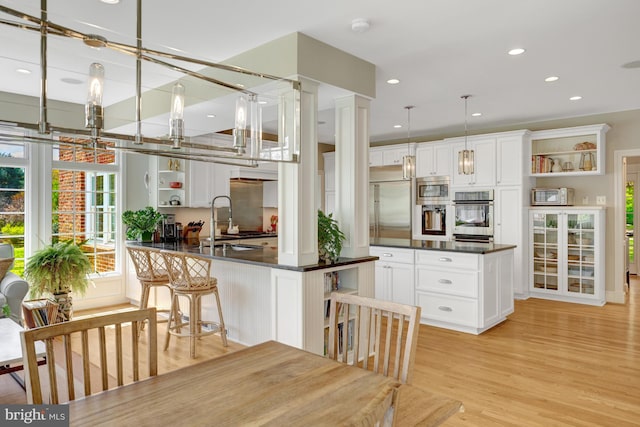 kitchen featuring built in appliances, open shelves, dark countertops, and white cabinets