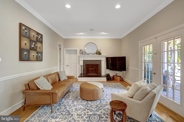 living room with baseboards, ornamental molding, wood finished floors, and a premium fireplace