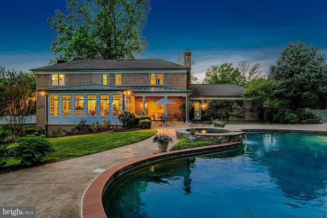 rear view of property featuring a standing seam roof, a chimney, fence, a yard, and a patio
