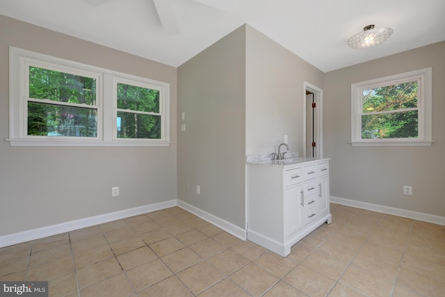unfurnished room with baseboards, a sink, ceiling fan, and light tile patterned flooring