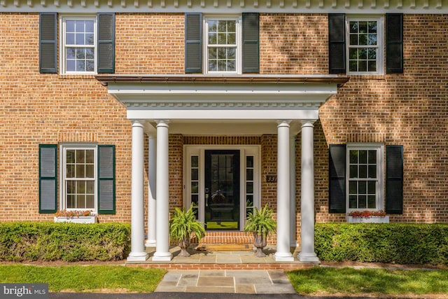doorway to property with covered porch and brick siding