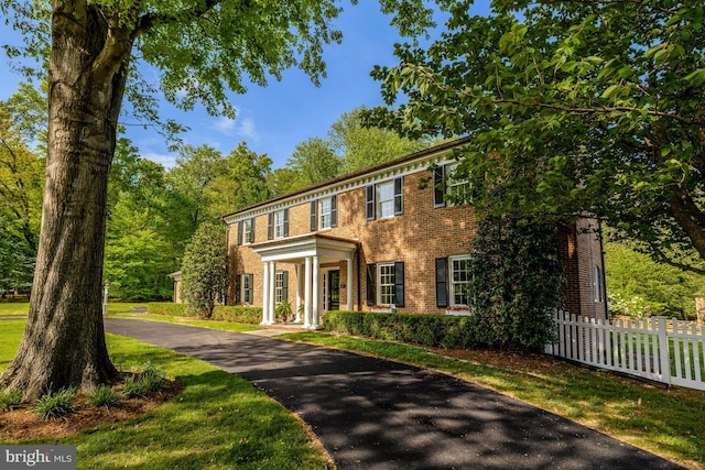 colonial home featuring brick siding and fence