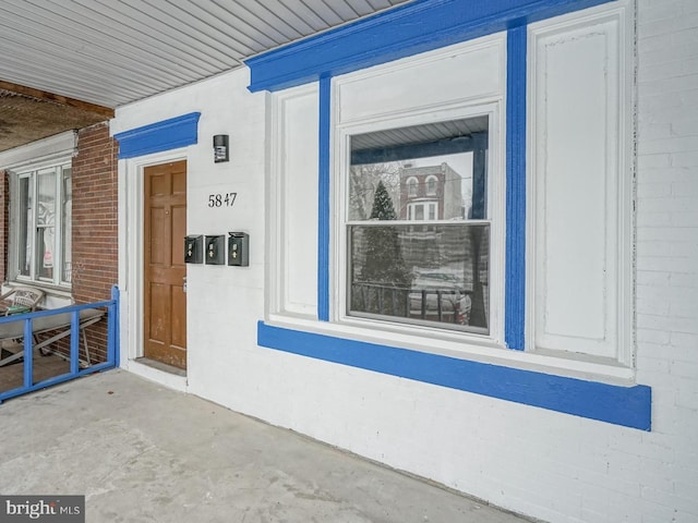 entrance to property with covered porch and brick siding