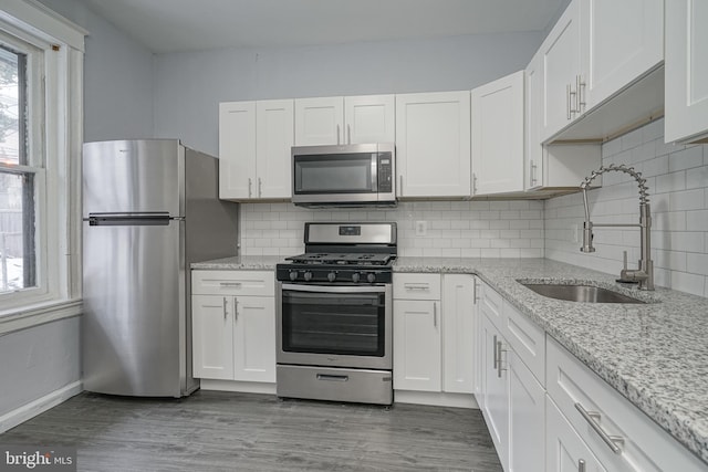 kitchen featuring a sink, appliances with stainless steel finishes, wood finished floors, and white cabinetry