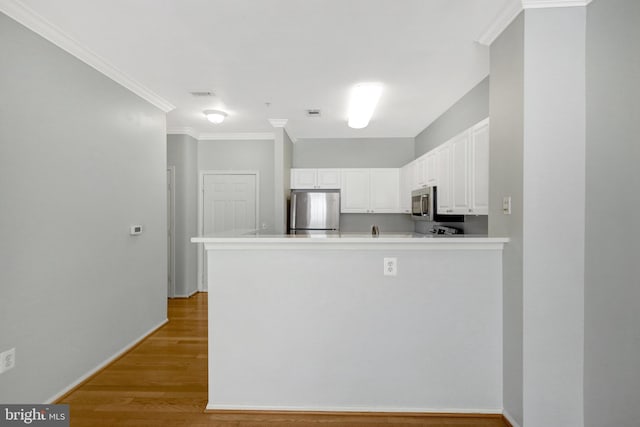 kitchen featuring crown molding, light wood-type flooring, a peninsula, stainless steel appliances, and white cabinetry