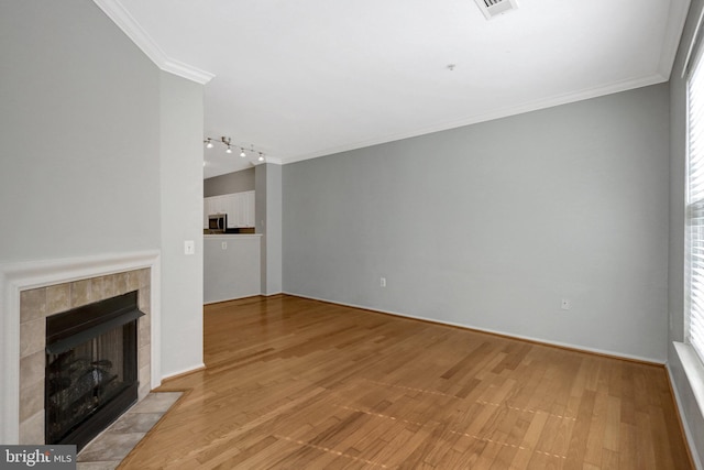 unfurnished living room with visible vents, crown molding, a tiled fireplace, and light wood finished floors