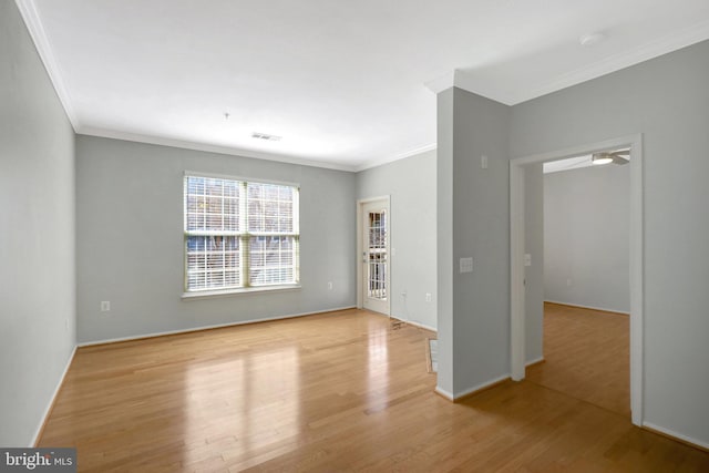 spare room featuring ornamental molding, baseboards, and wood finished floors