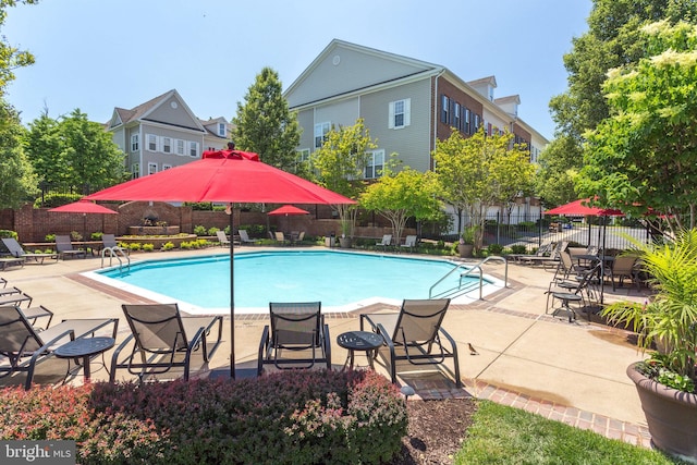 community pool with a patio area and fence