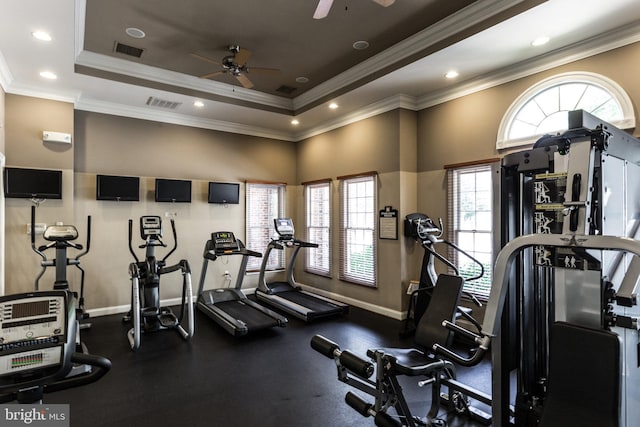 gym with a tray ceiling, crown molding, visible vents, and baseboards